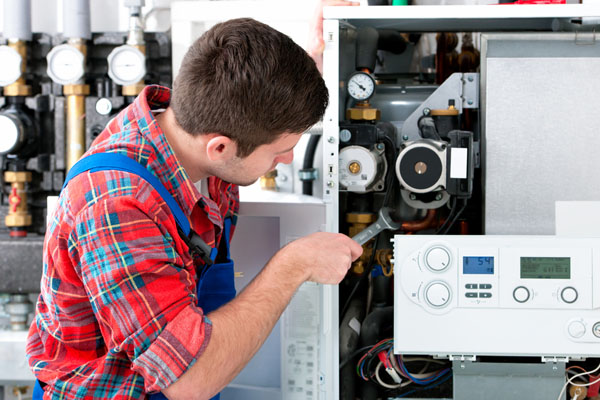 HVAC technician inspecting and repairing boiler controls in Colorado Springs