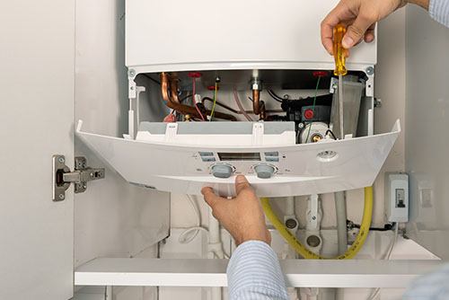 HVAC technician repairing an indoor boiler in Colorado Springs